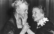 A monochrome archive image. The two women lean, smiling, towards each other. Helen reaches out her left hand to touch Eleanor Roosevelt's face while Roosevelt lightly guides Helen's arm.