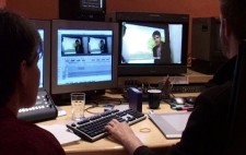 Liz sits in a post-production suite with an editor. In front of them are two monitors. One has a full-sized image from the film, with captions applied. The second shows two smaller versions of the same image, with an editing timeline below.