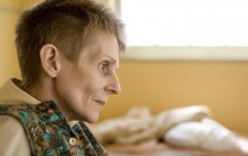 A profile photo in close up of one of the extras. Framed against the soft yellow of a distant wall, she gazes far distance, deep in thought.