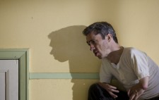 Mat Fraser crouches to the right of the frame, his shadow reflected large on the wall behind him.