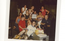 A polaroid of the 10 crew from the shoot, gathered in the film studio, surrounded by equipment. In front of them is a silver equipment carry case, on which beers and drinks are rested. They grin and pose for the camera.