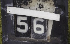 A battered blackboard with the words 'Water Temperature' painted on in white. Two metal labels in the centre of the board read '56'.