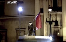 A SkyARTS screenshot shows Liz on her wheelchair and in black Nazi uniform holding aloft a red flag with black text.