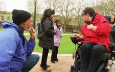Ralph and Liz in conversation with two children who move through the Square wearing large earphones.