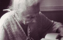 Helen  is frail, dressed in a knitted bed jacket, her white hair piled up on her head. She sits on a wheelchair, a Braille book balanced on its tray, as she leans forward, absorbed in her reading.