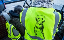 A member of the production team wears a high vis jacket with the Figures logo, a drawn figure, and the text #We Are Figures.