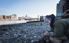 On a wide shingle foreshore, St Paul’s and the London skyline as a backdrop, Liz leans over a pile of clay, sculpting a figure.