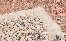 A hessian mat rests upon an expanse of crushed bricks, in reds and pinks. On the mat, the fired figures are piled, their colours echoing those of the landscape.