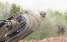 From the end of the milling machine, fragments of crushed figures are propelled into air.