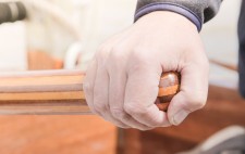 A hand rests on a wooden tiller.