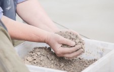 Above a crate of dust and pieces of the figures, cupped hands are filled with the remains.