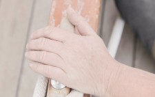 A dusty hand rests on a wooden boat cleat, a loop of rope running beneath it.