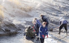 Members of the team dig mud from the riverbank with spades.