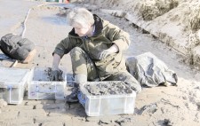 Liz sits on the slipway, filling crates with mud.