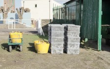 20 crates of mud, and some yellow tubs, are stacked, filled with mud.