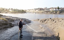 The slipway falls steeply down to the river at low tide, as a member of the sailing club hoses away the surface mud.