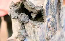 A close up of industrial machinery, painted blue and caked with mud.