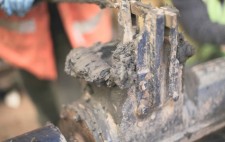 A close up of industrial machinery, painted blue and caked with mud.