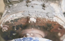 A close up of industrial machinery, painted blue and caked with dried mud.