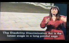 Screenshot from broadcast shows paving leading to a long flight of stone steps. Captions read 'The Disability Discrimination Act is the latest stage in a long painful saga'. To the right of screen is a BSL interpreter.